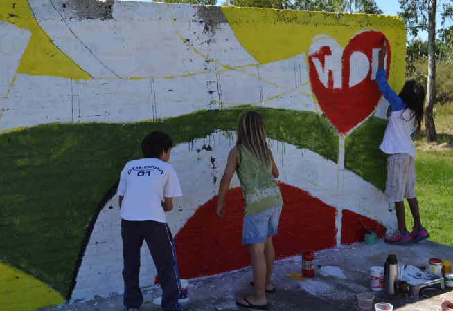 Niños pintando una pared en un barrio de Montevideo.